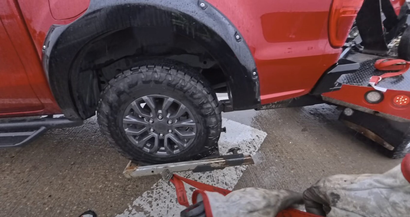 Red truck with flat tire being secured on a tow truck in Cardiff, CA